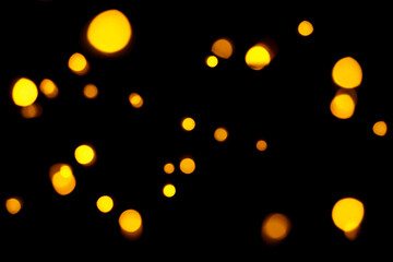 Gold bokeh on dark background. Defocused golden lights. New Year, Christmas background, abstract texture.