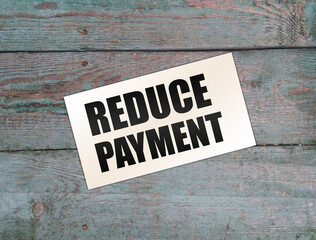 Reduce payment text on card on wooden background. business concept