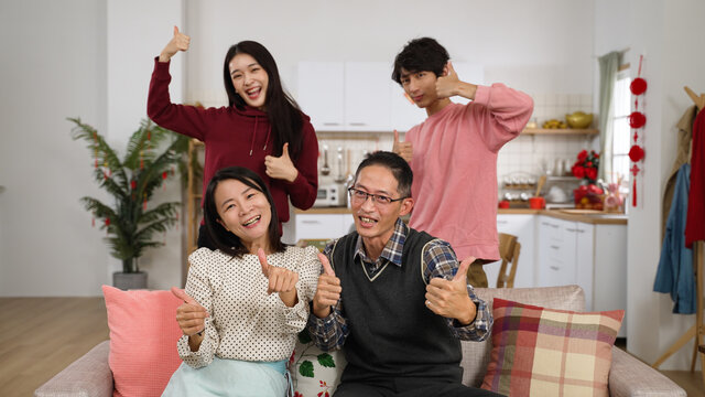 cheerful father. mother. adult daughter and son looking at camera and making thumb victory hand signs while taking burst shots at home during chinese spring festival