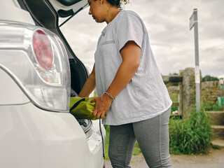 Woman loading gear into car trunk