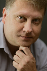 Portrait of an adult male history teacher on a black background in a blue shirt.