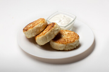 Cottage cheese cheesecakes, fried cheesecakes on a white plate. Cheesecakes on a light background