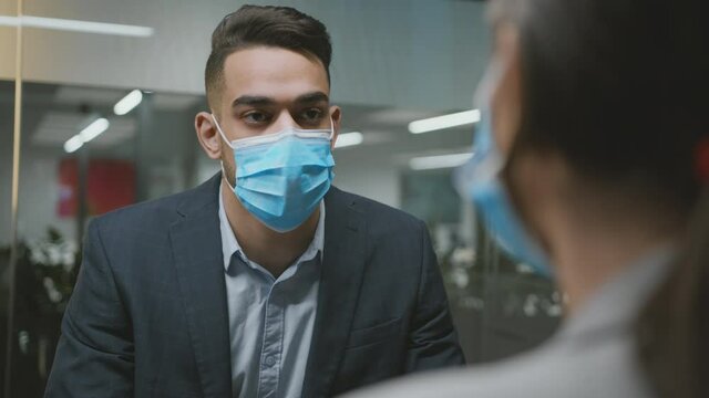 Pandemic and employment concept. Young man hr wearing protective face mask talking with female job seeker at office