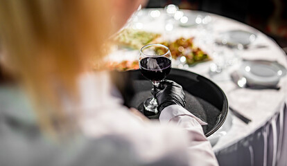 Fototapeta na wymiar Waiter holding tray with red wine glass