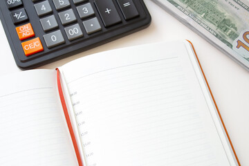 Calculator notepad and stack of money on white background