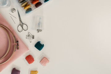 Accessories for cross stitch are on a white table, flat lay.