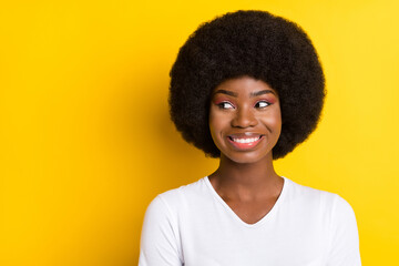 Photo of cheerful young dark skin woman look empty space smile imagine isolated on yellow color background