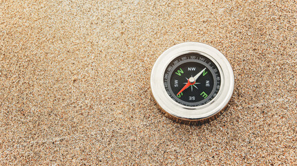 A compass on smooth sandy beach background. Exploration and adventure concept. Vacation on the tropical sea. The backdrop and copy space for the tourism and the travel industry.