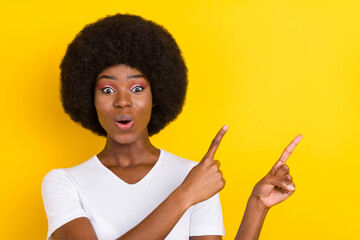 Photo of amazed nice dark skin young happy woman point fingers news empty space isolated on yellow color background