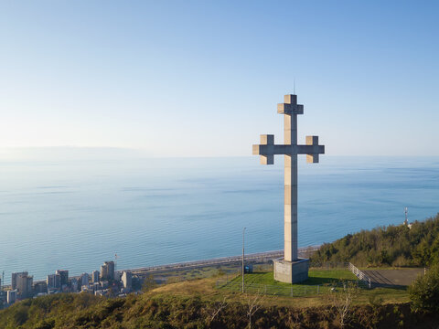 Drone view of the Orthodox cross on the mountain against the background of the sea on a sunny evening, Georgia. Concept of freedom, Christianity, Orthodoxy