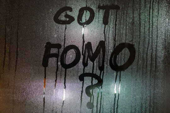 the question got FOMO - fear of missing out - handwritten on night wet window glass surface with bliurry street lights