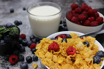 Breakfast with muesli, raspberries, blueberries on a dark concrete table.