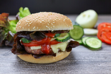 Home made hamburger with lettuce, cucumber,onion  and cheese ,closeup on a wooden rustic table