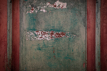 Multicolor old wooden texture background. Scratched, aged, weathered house door panel detail with peeled off paint. Dark, moody backdrop. Brown, red, burgundy and emerald green wood surface