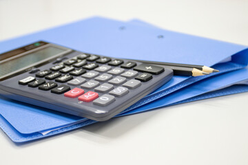 calculator with file folder on table in work office, concepts business and cost and financial planning selective focus calculator