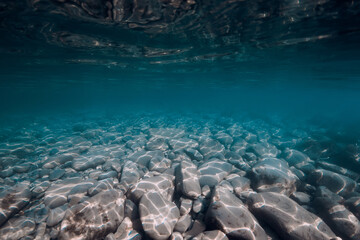 Underwater view with stones bottom in turquoise water.