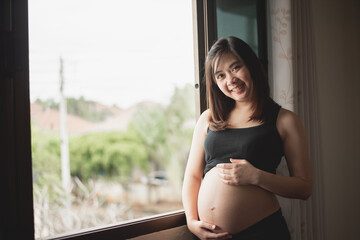 Asian pregnant woman holds her hands on her swollen belly. Pregnant woman feeling happy love at...