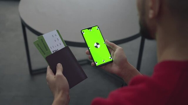 Travel and vacation. Unrecognizable guy carrying passport and boarding pass and smartphone with green chroma key screen