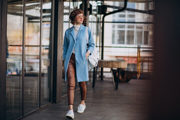 Fototapeta premium Young woman model in blue coat by the cafe