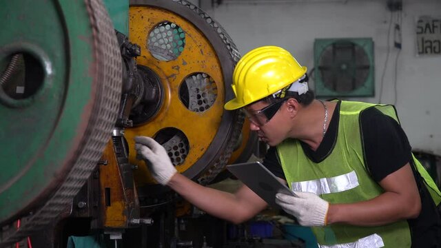 asian mechanic repairing big heavy industry machine . engineer maintenance machinery in Large Industrial Factory. young worker checking or inspection working machine at site indoors