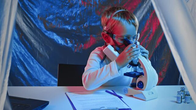 A little sientist, virusologist in a protective mask on the invention of a vaccine, a cure in a laboratory