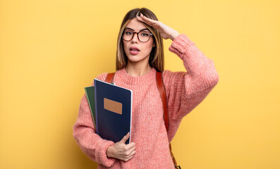 pretty student woman looking happy, astonished and surprised. books and backpack