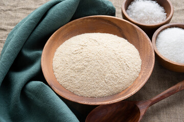 Amaranth flour with a spoon in wooden bowl on linen background