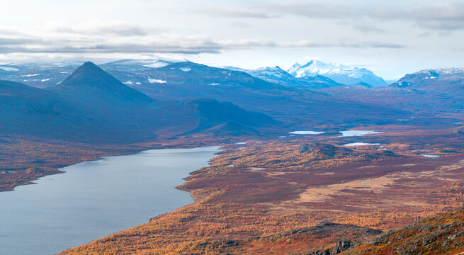 Epic view of vast arctic landscape of Stora Sjofallet National Park, Sweden, on autumn day. Remote mountains and valleys of Lapland. Ahkka massif in the back. View from the top of Lulep Gierkav.