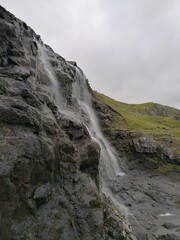 Fototapeta na wymiar Stunning waterfalls with white streams coming down over black lava rocks on the Faroe Islands 