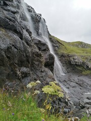 Stunning waterfalls with white streams coming down over black lava rocks on the Faroe Islands 