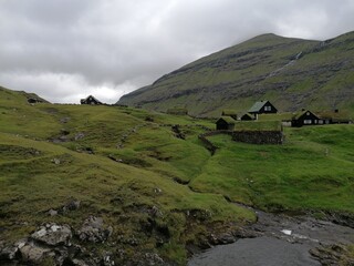 Fototapeta na wymiar Traditional old cute stone houses with grass roofs on the Faroe Islands with a mountain view