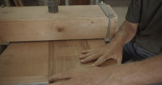 Carpenter pulls and files back a wooden plank