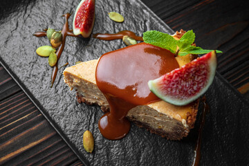 Cheesecake on a dark stone, wooden background, with mint and figs