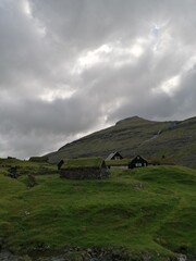 Traditional old cute stone houses with grass roofs on the Faroe Islands with a mountain view