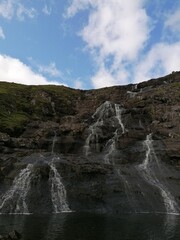 Fototapeta premium Stunning waterfalls with white streams coming down over black lava rocks on the Faroe Islands 