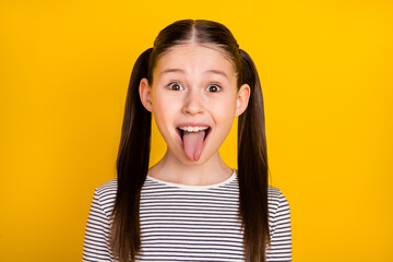 Photo of young school girl happy positive smile grimace tongue-out isolated over yellow color background - obrazy, fototapety, plakaty