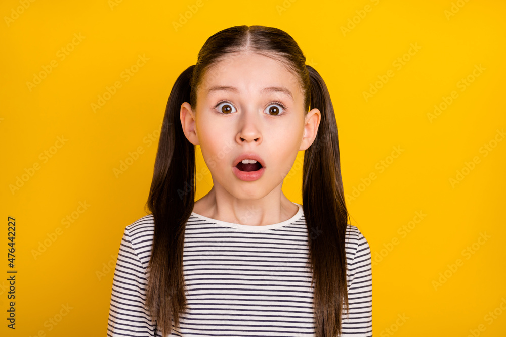 Sticker Photo of young school girl amazed surprised afraid scared fail mistake isolated over yellow color background