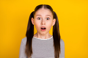 Photo of young school girl amazed surprised afraid scared fail mistake isolated over yellow color...