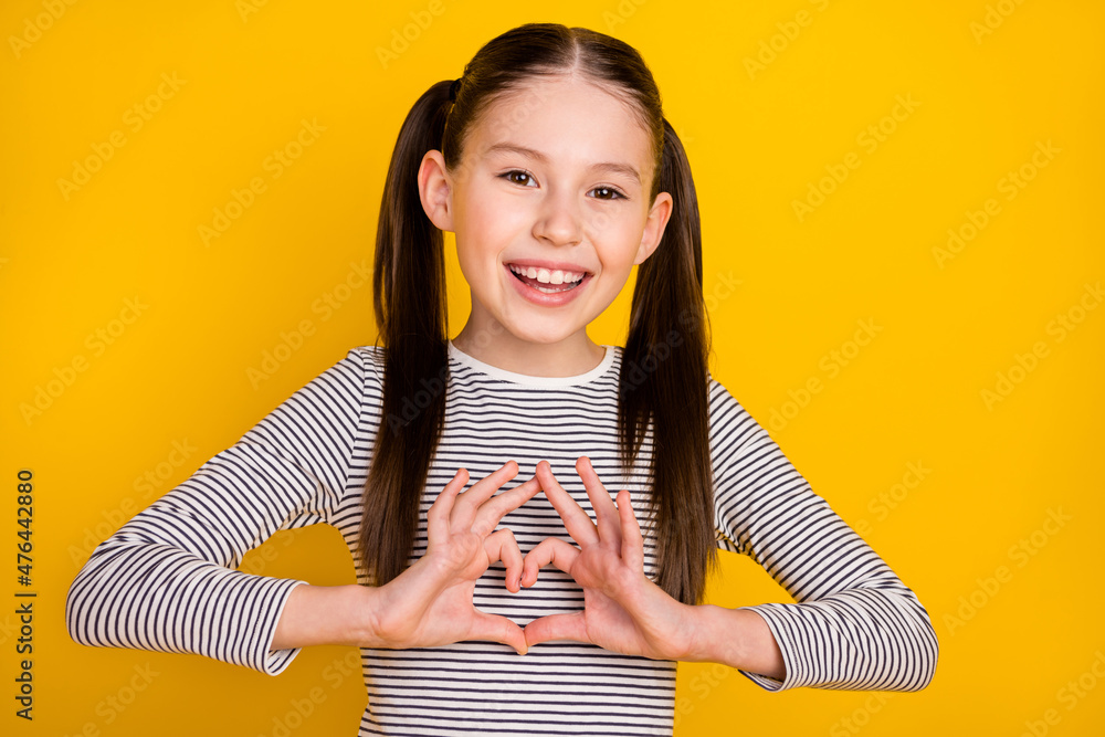 Sticker Photo of young attractive school girl show fingers heart symbol love romantic isolated over yellow color background