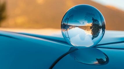 Crystal ball alpine summer landscape shot with reflections on a car roof near Lermoos, Tyrol, Austria