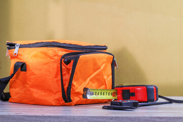 orange bag yardstick calipers and orange construction helmet on a table