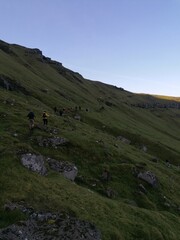 Fototapeta na wymiar A group of hikers on a green mountain ridge walk in the Faroe Islands