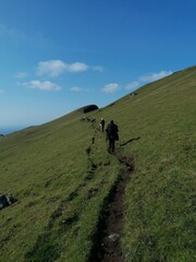 Fototapeta na wymiar A group of hikers on a green mountain ridge walk in the Faroe Islands