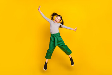 Full size photo of young excited girl happy positive smile have fun jump up isolated over yellow color background