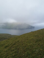 Mountain Hiking in the lush a green hills of the misty Faroe Islands