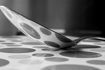 black and white metal spoon with reflections on ground