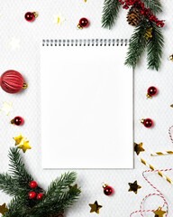 Christmas background with notebook paper, fir tree branches, and festive decor. Flat lay and top view. Christmas and New Year resolutions concept.