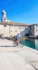 A man in blue tank top and a full cap standing on her bike and admiring the view on the...