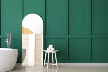 Mirror with reflection of folding screen near green wall in bathroom