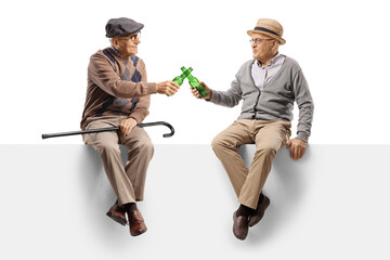 Elderly men sitting on a blank panel and toasting with beer bottles